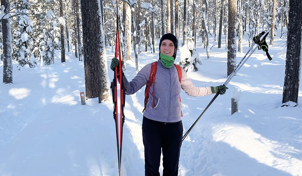 Tiina Vainio-Kaila talvisessa metsässä suksien kanssa. 