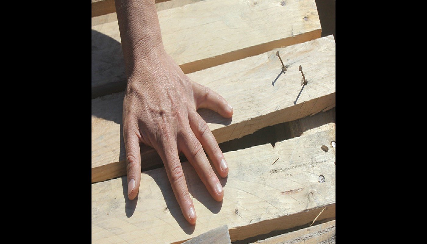 Käsi koskettaa puisia lautoja. 
