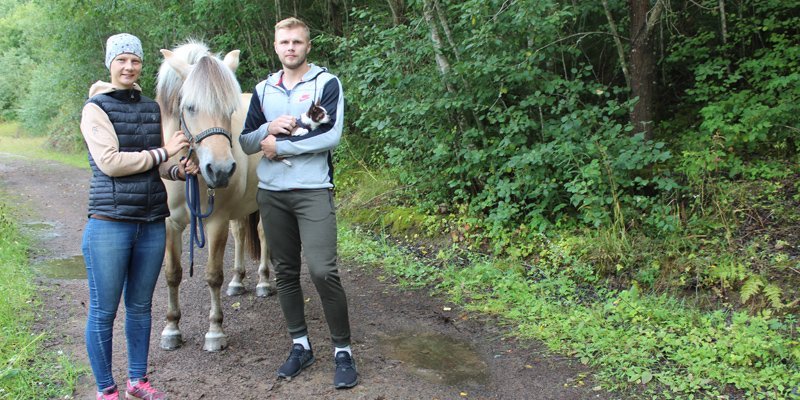 Salla ja Samu Jokela seisovat hevosen kanssa metsäpolulla. Ympärillä on rehevää kesäistä metsää.