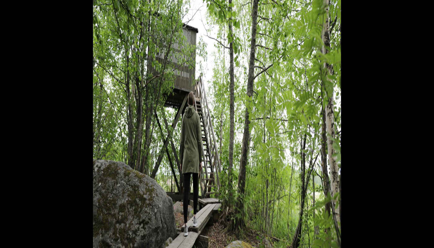 Retkeilijä kulkee kohti lintutornia kesällä. 