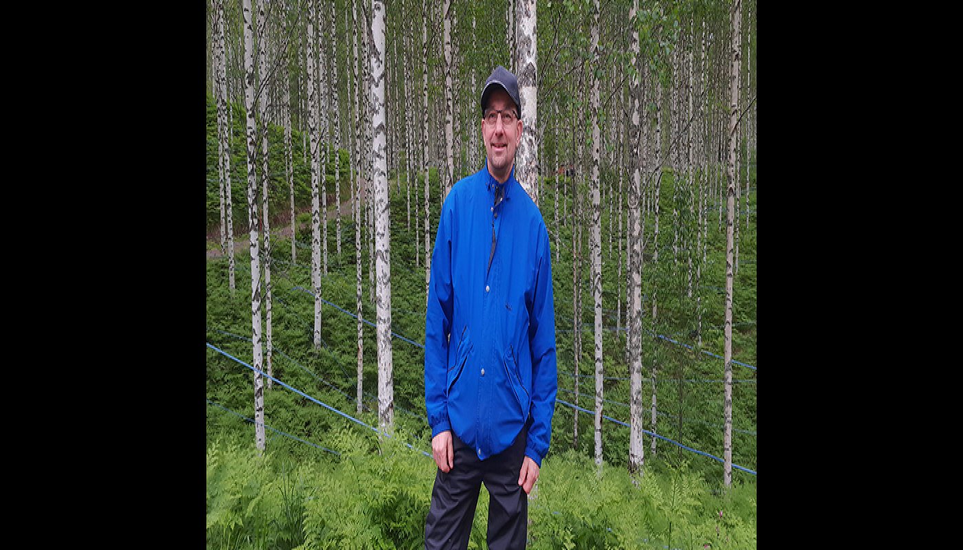 Kauko Kärkkäinen seisoo koivikon edessä.