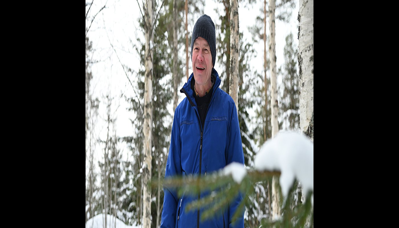 Tapani Isotalo seisoo talvisessa metsässä. Taustalla on koivuja ja kuusia.