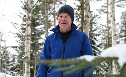 Tapani Isotalo seisoo talvisessa metsässä. Taustalla on koivuja ja kuusia.