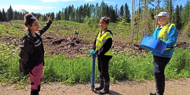 Nainen esittelee istutuskohdetta kahdelle nuorelle. 