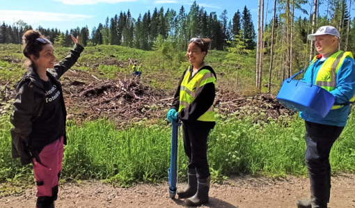 Nainen esittelee istutuskohdetta kahdelle nuorelle.