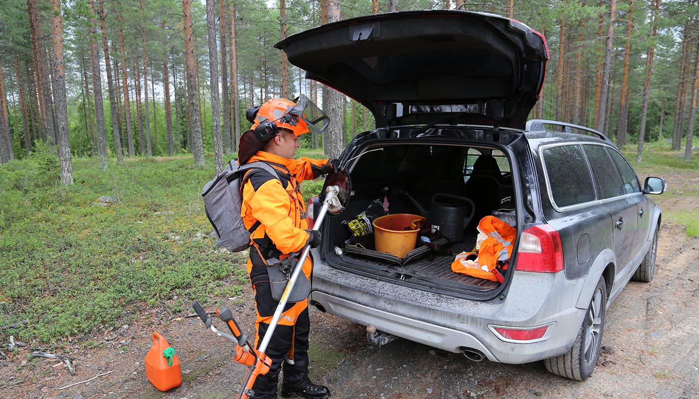 Sakari Mantila pakkaa työvälineitään auton takakonttiin metsätien varressa. 

