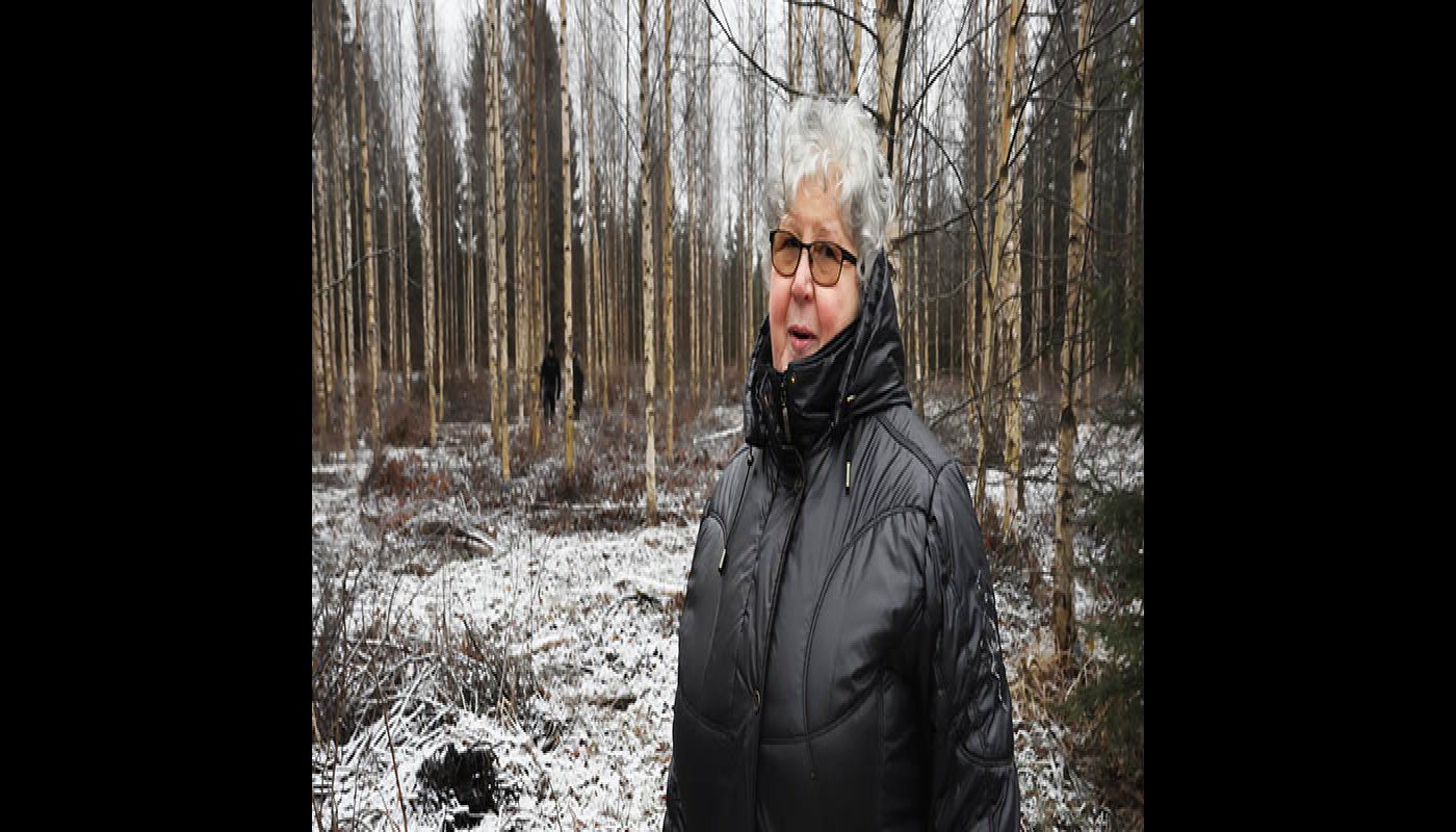 Kaisa Kolehmainen ja taustalla pellolle kasvanut koivikko.