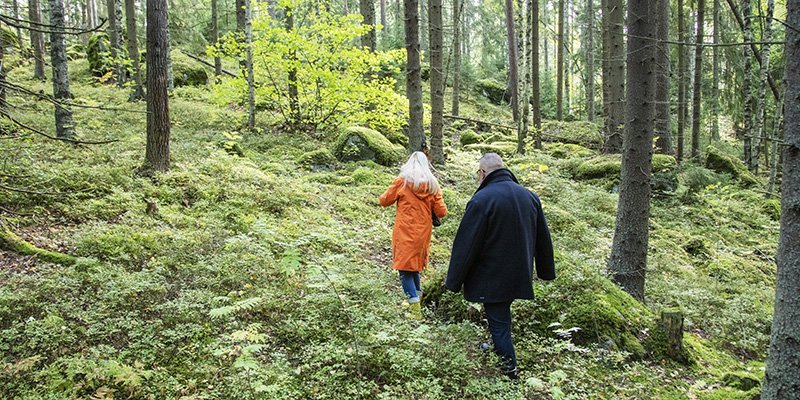 Nainen ja mies kulkevat metsässä peräkkäin. 