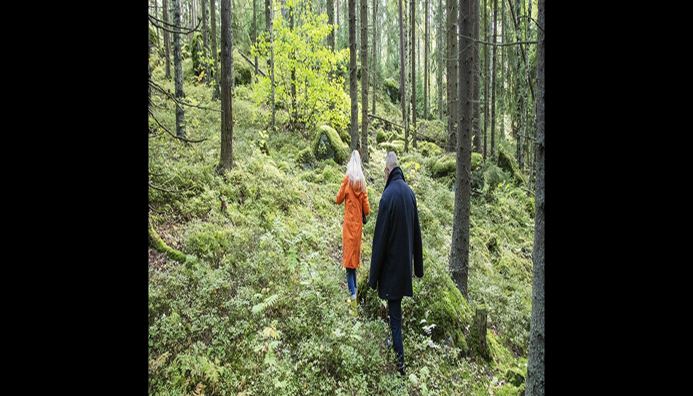 Nainen ja mies kulkevat metsässä peräkkäin. 