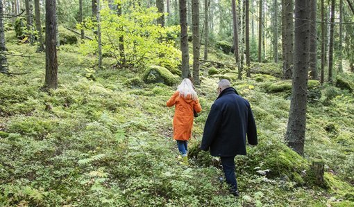 Nainen ja mies kulkevat metsässä peräkkäin. 