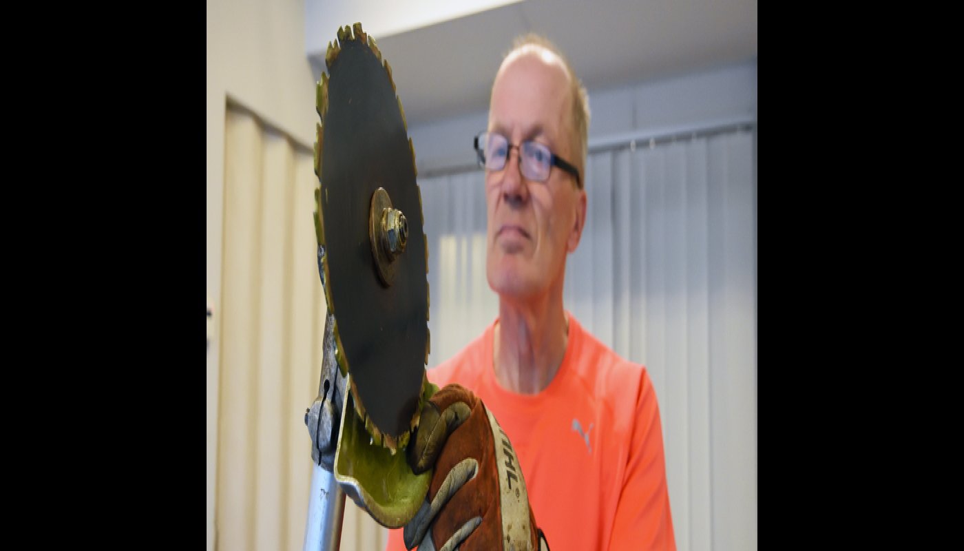 Jarmo Lepola katselee raivaussahan terää ja sen kuntoa.