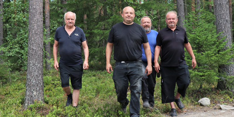 Reijo, Toni, Jani ja Mika Peräkangas kävelevät rinnakkain metsässä.