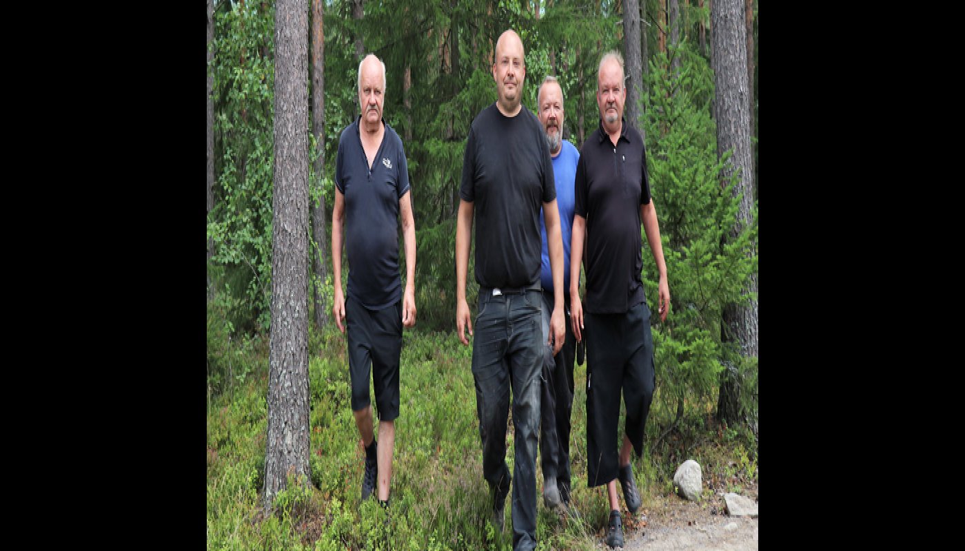 Reijo, Toni, Jani ja Mika Peräkangas kävelevät rinnakkain metsässä. 