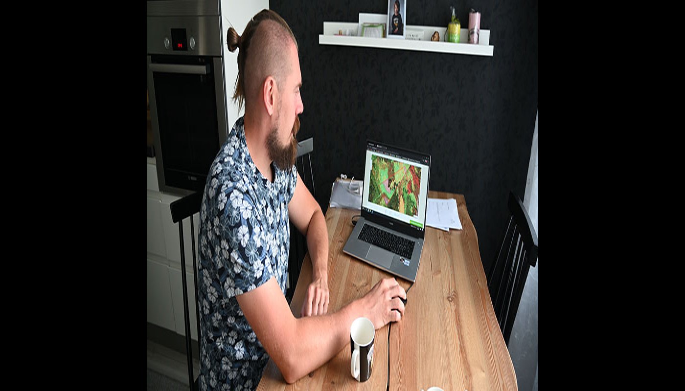 Tuomas Vakkila katsoo keittiön pöydän ääressä kannettavalta tietokoneelta Metsään.fi-palvelua ja oman metsänsä tietoja. 