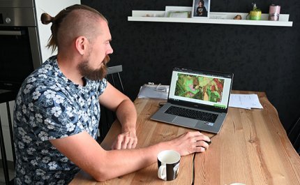 Tuomas Vakkila katsoo keittiön pöydän ääressä kannettavalta tietokoneelta Metsään.fi-palvelua ja oman metsänsä tietoja. 