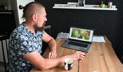 Tuomas Vakkila katsoo keittiön pöydän ääressä kannettavalta tietokoneelta Metsään.fi-palvelua ja oman metsänsä tietoja.