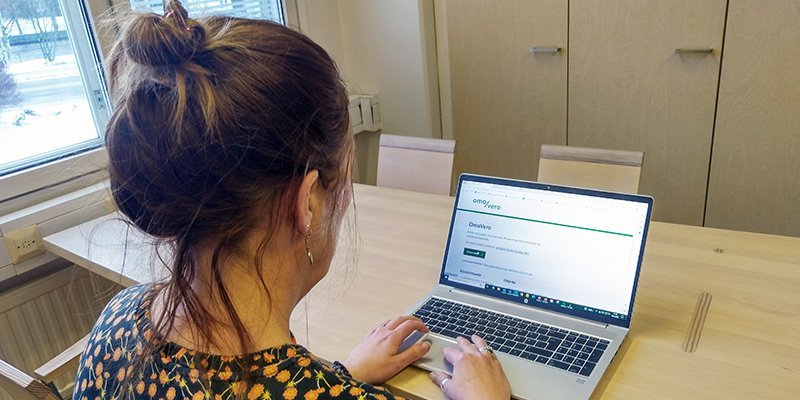 Nainen katsoo kannettavalta tietokoneelta OmaVero-palvelua puisen pöydän ääressä.