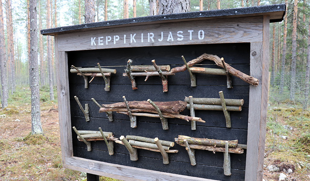 Metsässä on kyltti, jossa lukee ”keppikirjasto”. Keppikirjastossa on keppejä, joita voi heittää koirille. 