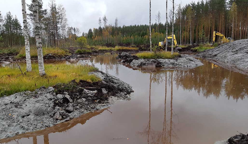 Kaksi kaivinkonetta kaivaa kosteikkoa.