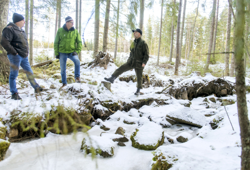 Visa Mikkola, Pentti Pakarinen ja Mika Tuomola seisovat ja juttelevat luonnontilaisen puron vieressä. Maassa on lunta..