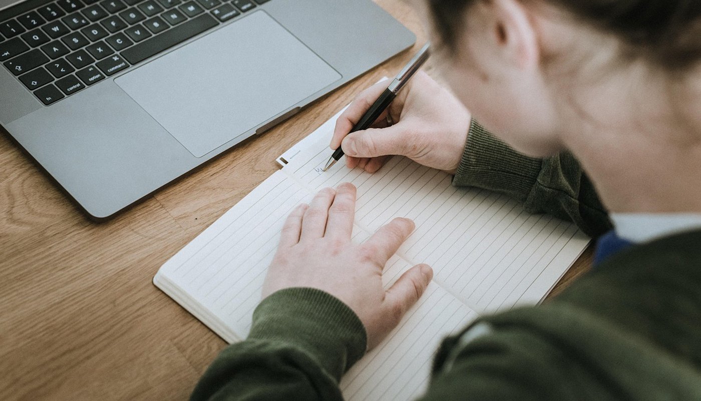 Henkilö kirjoittaa paperille muistiinpanoja