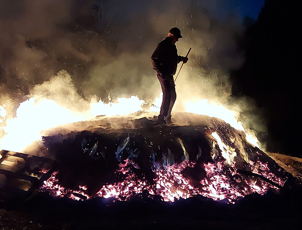 Tervahauta palaa yöllä ja mies vartioi haudan päällä palamista. 