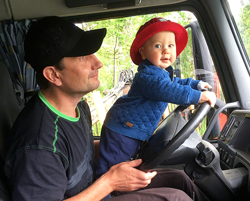 Timo Pesosen 1-vuotias Aari-poika on isänsä sylissä ja kääntää metsäkoneen rattia. 